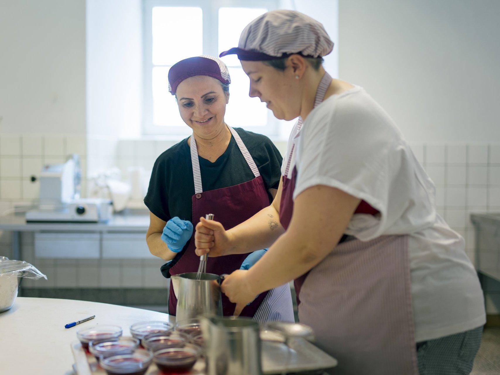 Zwei Mitarbeiterinnen arbeiten gut gelaunt in der Küche.